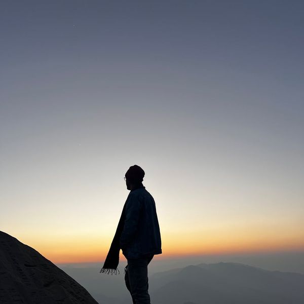 A silhouette of a man stretching against a sunrise.